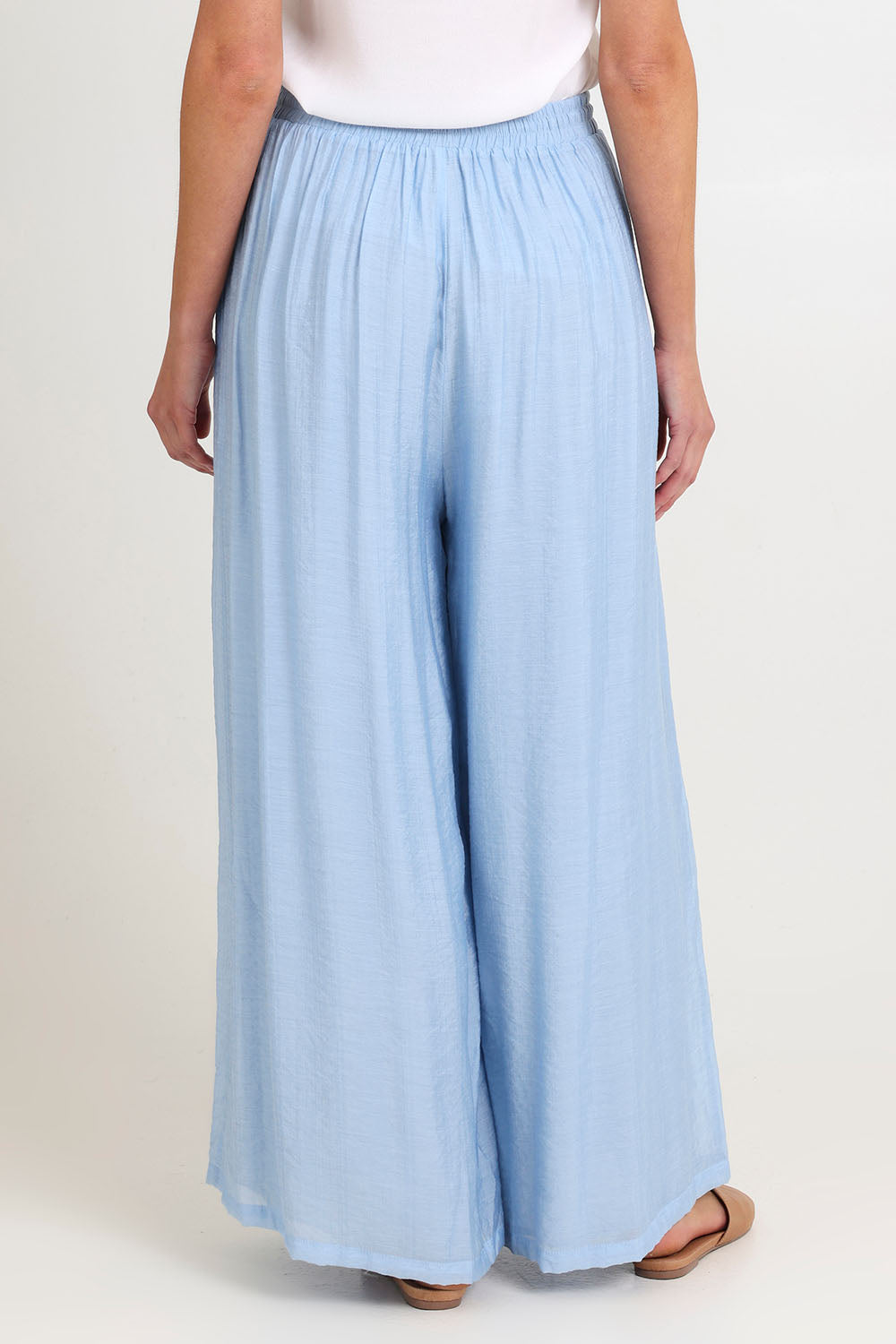 Model Madeline wearing size S of the Baja Pant in colour Safira (Blue), from the back