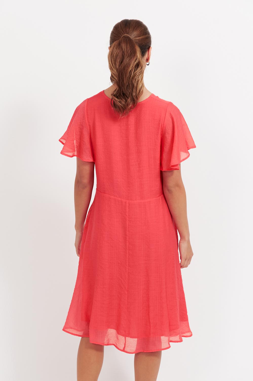 A model wearing the Baja Dress in colour Punch (Red), from the back