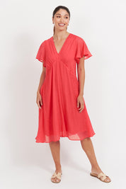 A model wearing the Baja Dress in colour Punch (Red), from the front, showing the whole outfit