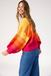 A model wearing the Valenza Jumper in colour Sunrise, from the front, cropped image