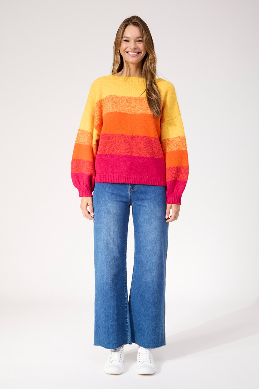 A model wearing the Valenza Jumper in colour Sunrise, from the front, showing the whole outfit