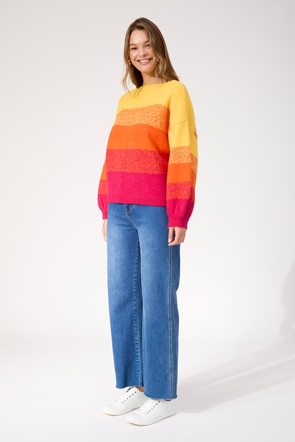A model wearing the Valenza Jumper in colour Sunrise, from the front, showing the whole outfit