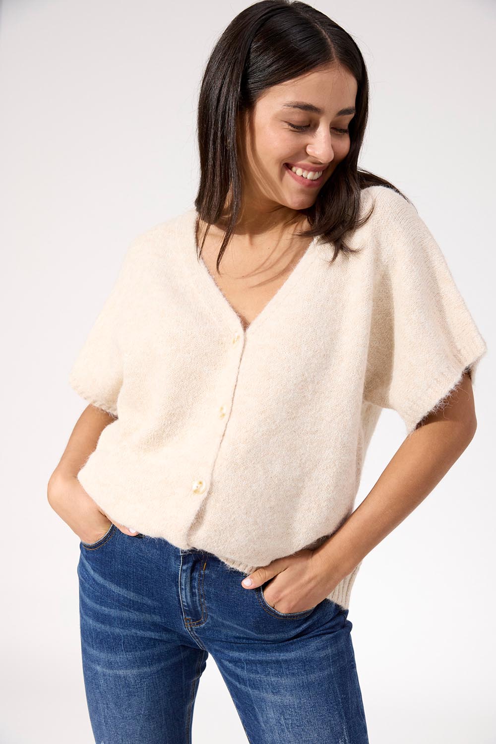 A model wearing the Valenza Knit Vest in colour Natural, from the front, cropped image
