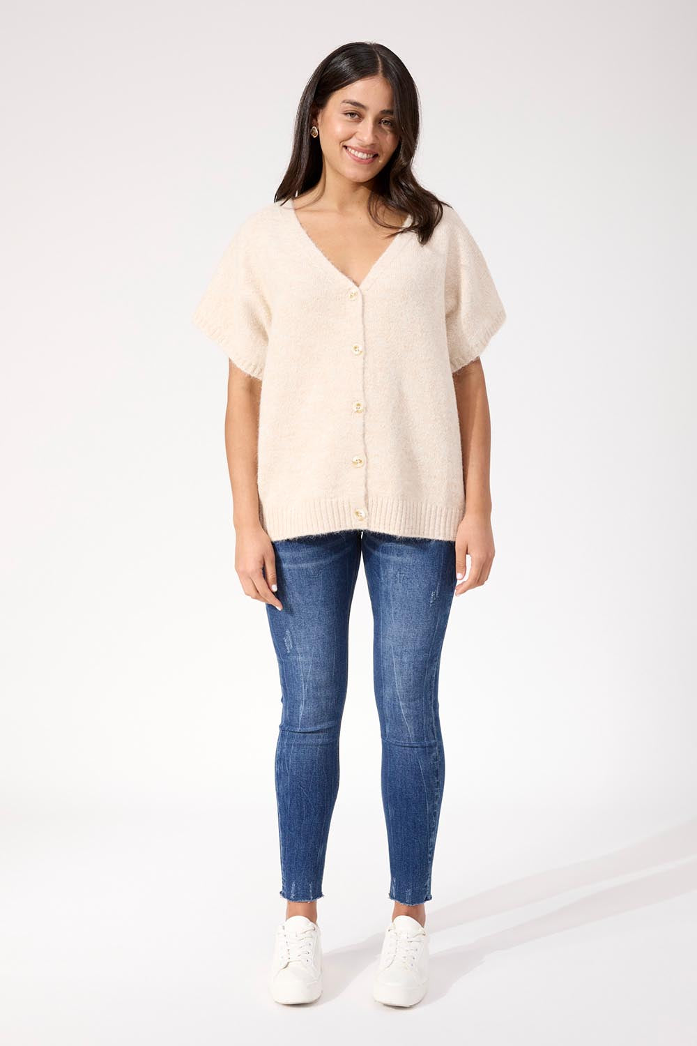 A model wearing the Valenza Knit Vest in colour Natural, from the front, showing the whole outfit