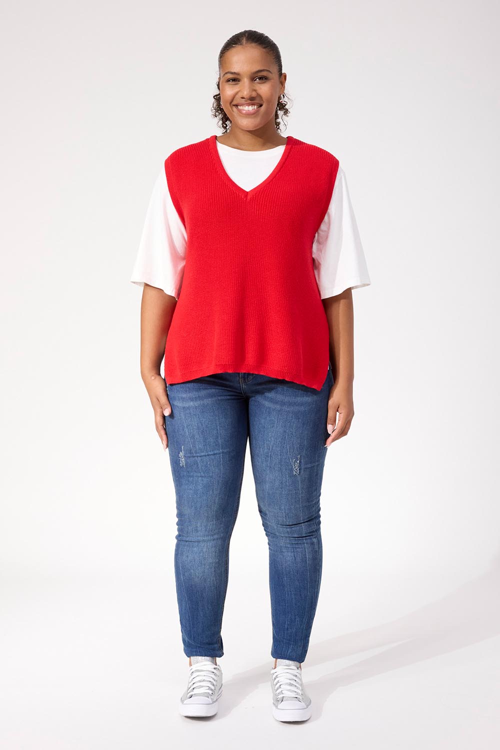 A model wearing the Alaska Knit Vest in colour Red (Red), from the front, showing the whole outfit