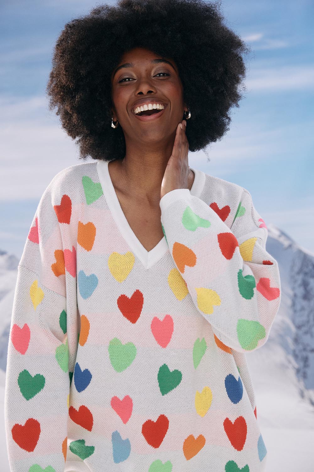 A model wearing the Alaska Relaxed Heart Jumper in colour Rainbow, from the front, showing the whole outfit