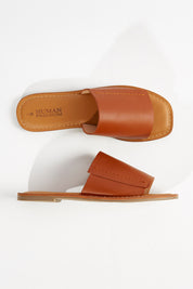 A model wearing size 7 of the Oats Leather Slide in colour Darktan, from the front, showing the whole outfit