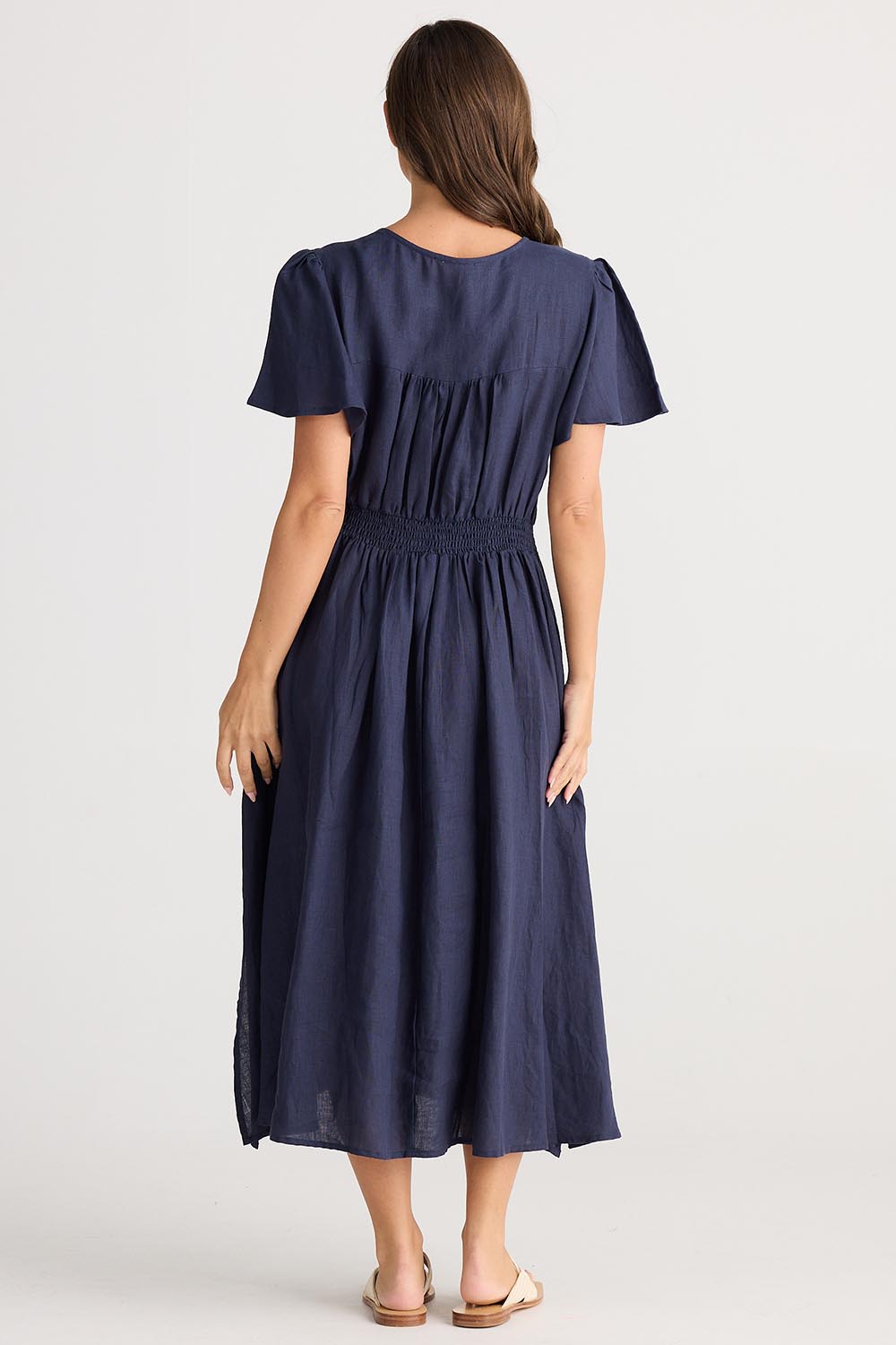 A model wearing the Blossom Linen Dress in colour Navy (Blue), from the back