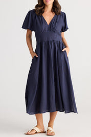 A model wearing the Blossom Linen Dress in colour Navy (Blue), from the front, cropped image