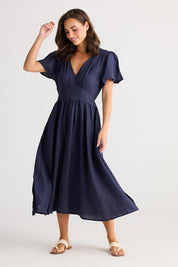 A model wearing the Blossom Linen Dress in colour Navy (Blue), from the front, showing the whole outfit