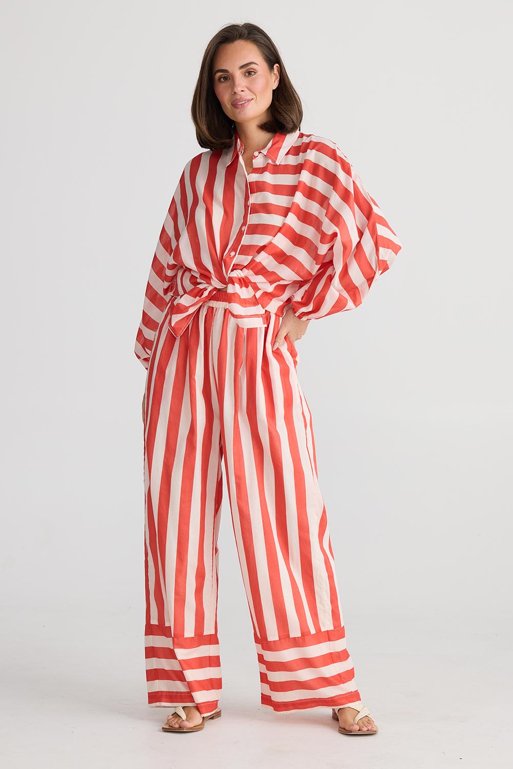 A model wearing the Mariah Cotton Pant in colour Noelstripe (Red), from the front, showing the whole outfit