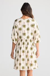 A model wearing the Alfina Dress in colour Ivorypalm, from the back