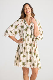 A model wearing the Alfina Dress in colour Ivorypalm, from the front, cropped image