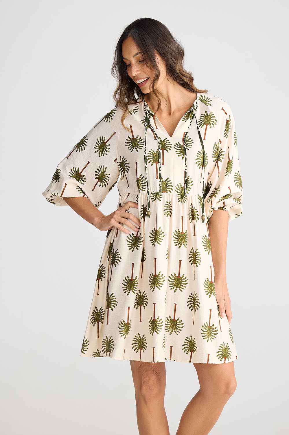 A model wearing the Alfina Dress in colour Ivorypalm, from the front, cropped image