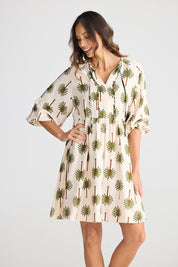 A model wearing the Alfina Dress in colour Ivorypalm, from the front, cropped image