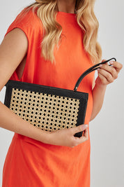A model wearing the Raffles Clutch in colour Black, from the front, showing the whole outfit