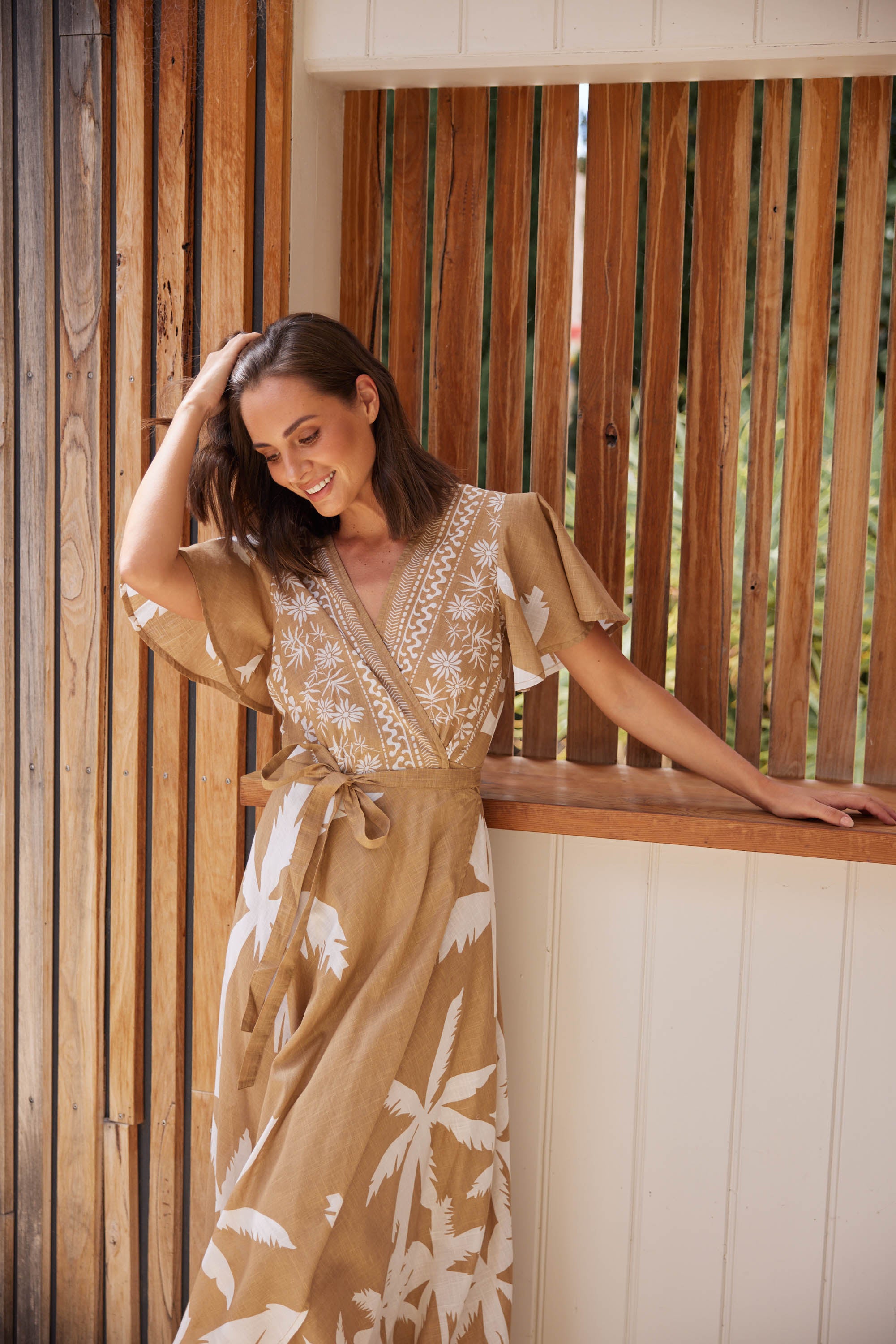 A model wearing the Tropics Wrap Dress in colour Haven, from the front, showing the whole outfit
