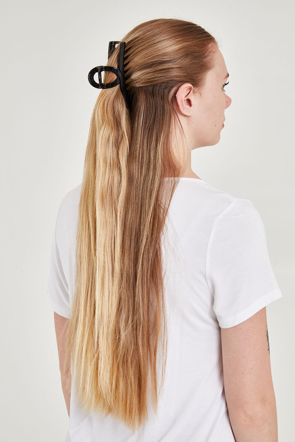 A model wearing the Slider Hair Clip in colour Black (Black), from the front, cropped image