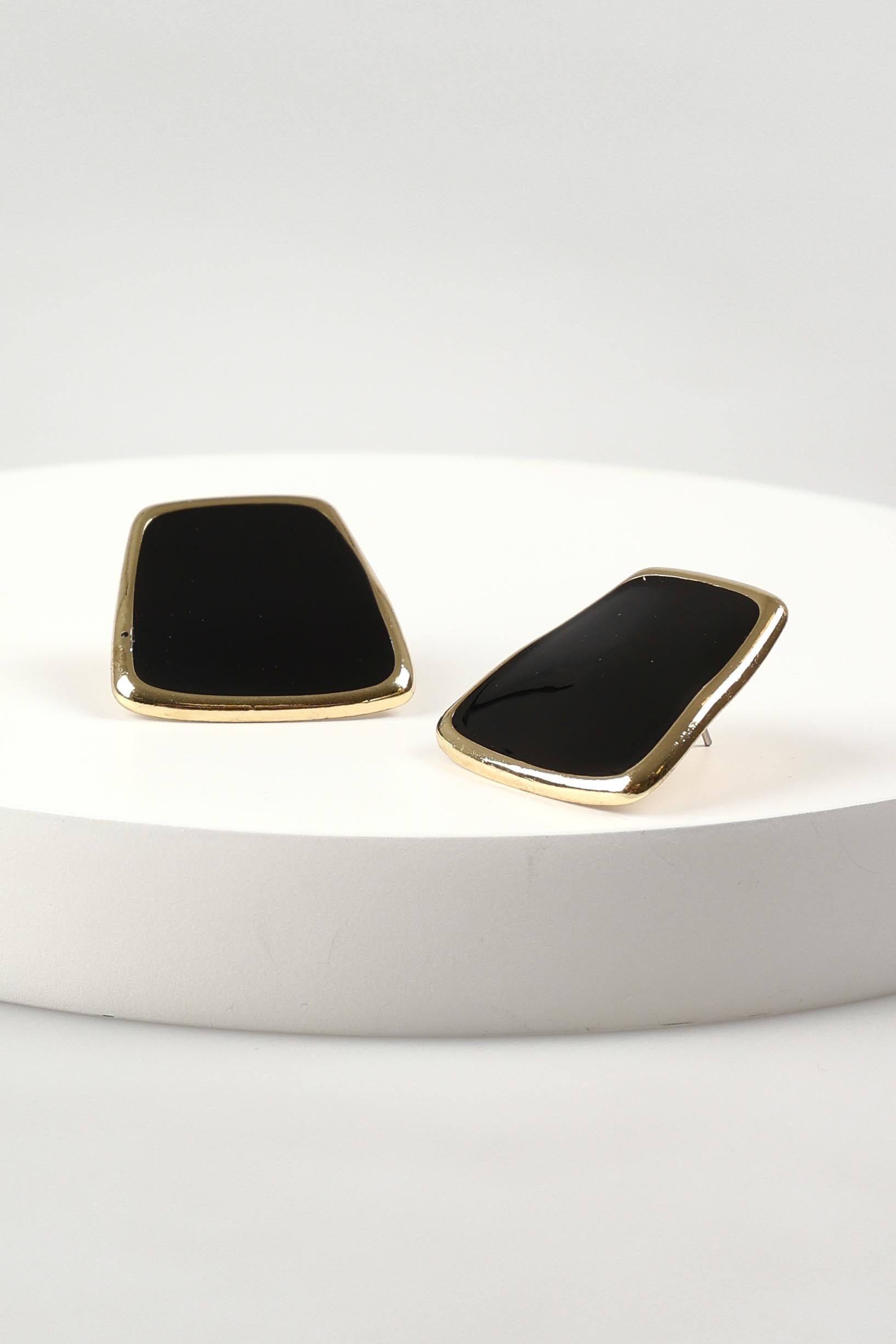 A model wearing the Fleur Earrings in colour Black (Black), from the front, showing the whole outfit