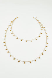 A model wearing the Cosmos Necklace in colour Gold (Metallics), from the front, showing the whole outfit
