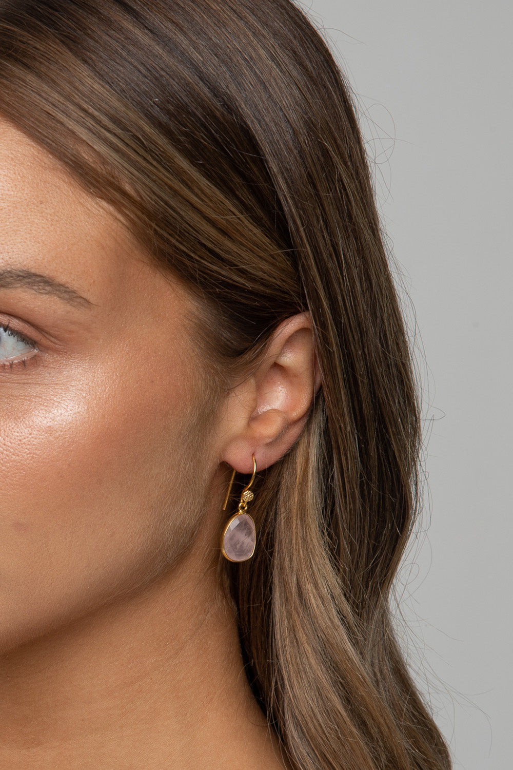 A model wearing the Carrie Earrings in colour Rose (Pink), from the front, cropped image