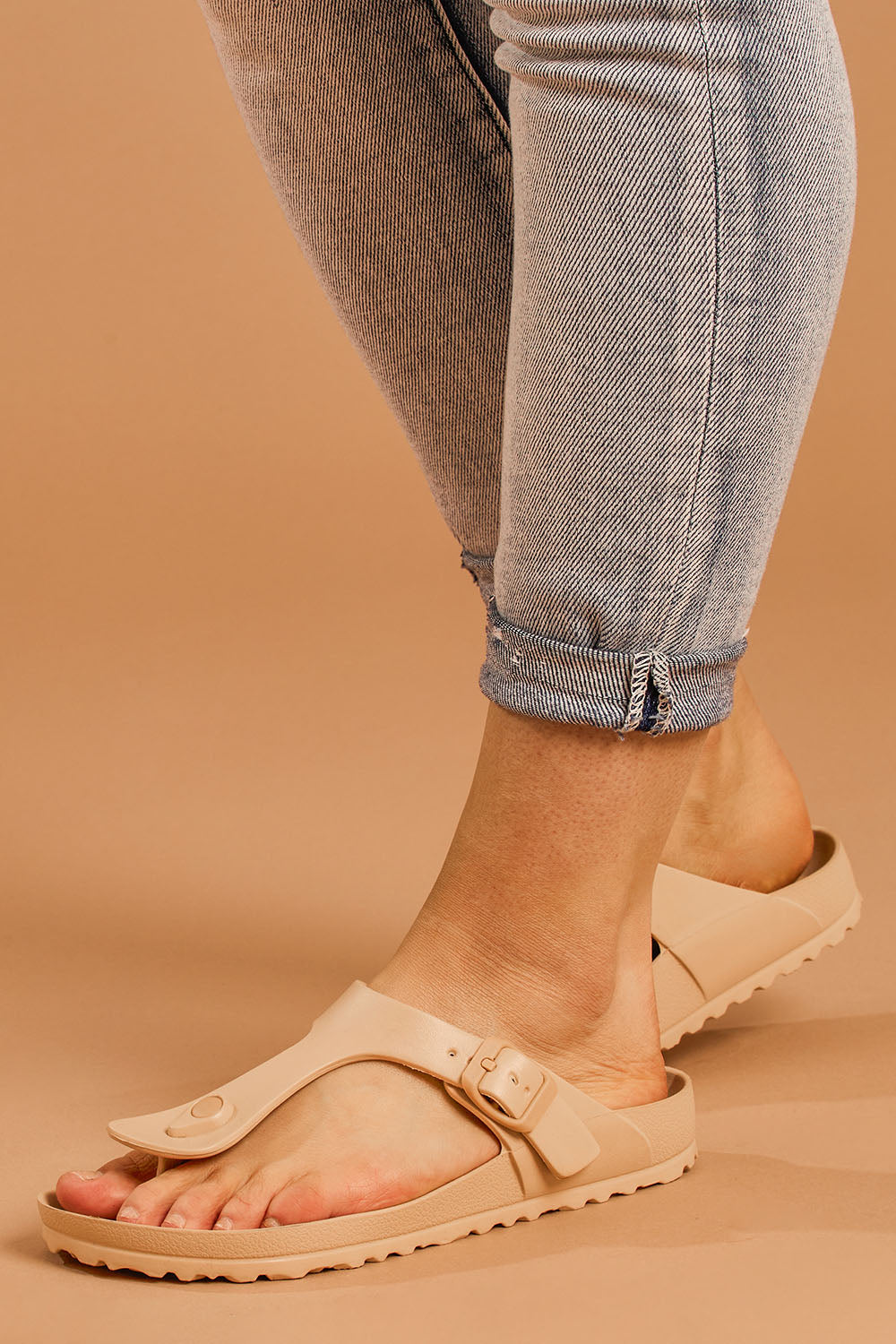 A model wearing size 8 of the Coastal EVA Slide in colour Tan, from the front, cropped image
