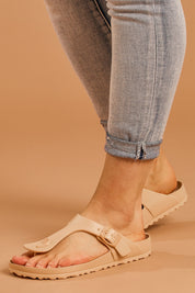 A model wearing size 8 of the Coastal EVA Slide in colour Tan, from the front, cropped image