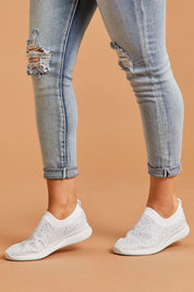 A model wearing size 8 of the Firefly Sneaker in colour White (White), from the front, cropped image