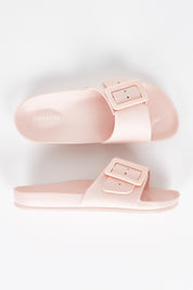 A model wearing size 7 of the Solace EVA Slide in colour Blush (Pink), from the front, showing the whole outfit