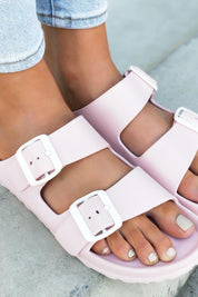A model wearing the Sundreamer EVA Slide in colour Blush (Pink), from the front, showing the whole outfit