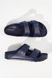 A model wearing size 6 of the Sundreamer EVA Slide in colour Navy (Blue), from the front, showing the whole outfit