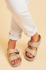 A model wearing size 7 of the Sundreamer EVA Slide in colour Sand, from the front, cropped image
