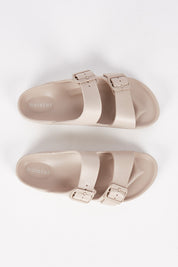 A model wearing size 7 of the Sundreamer EVA Slide in colour Sand, from the front, showing the whole outfit