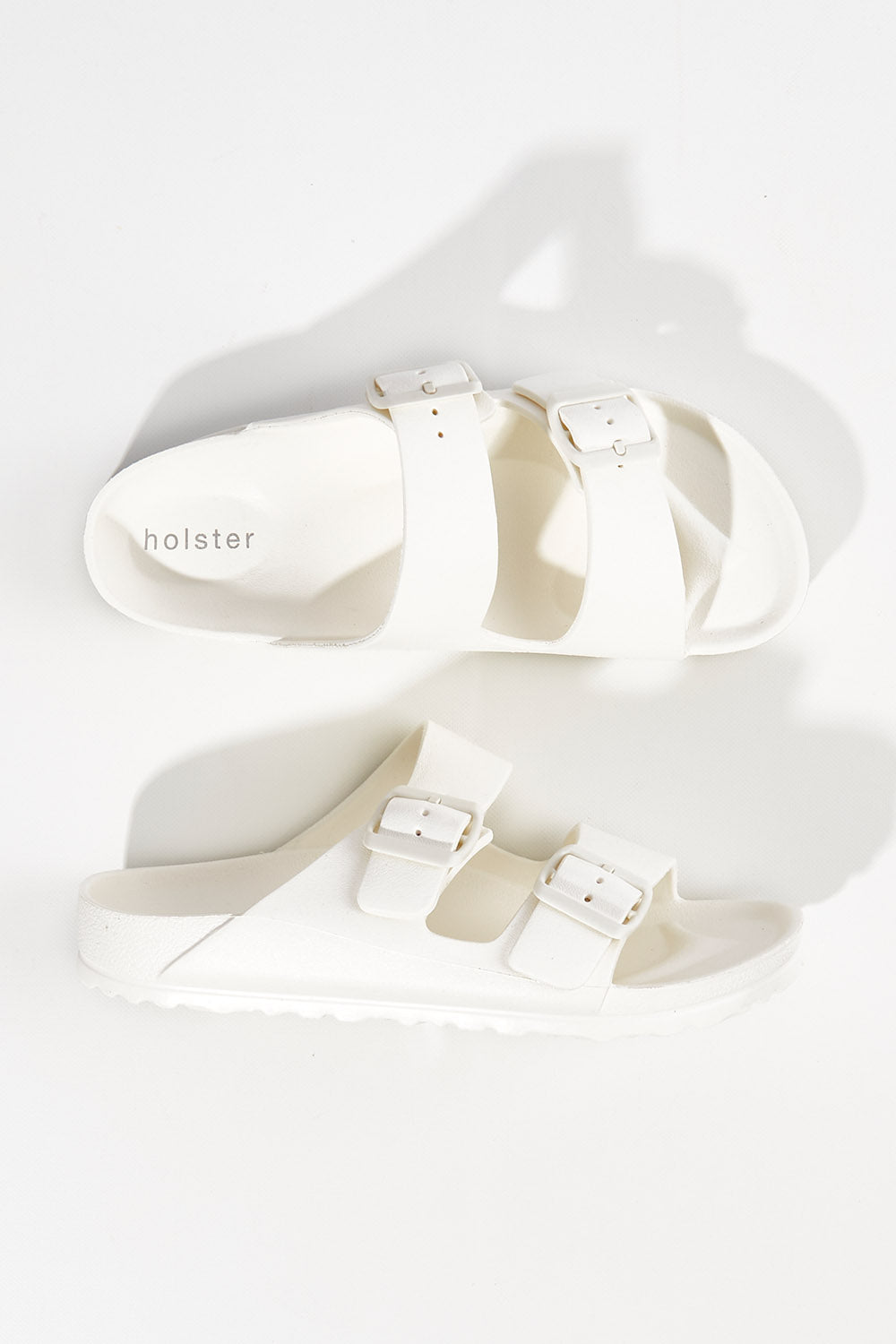 A model wearing size 6 of the Sundreamer EVA Slide in colour White (White), from the front, showing the whole outfit