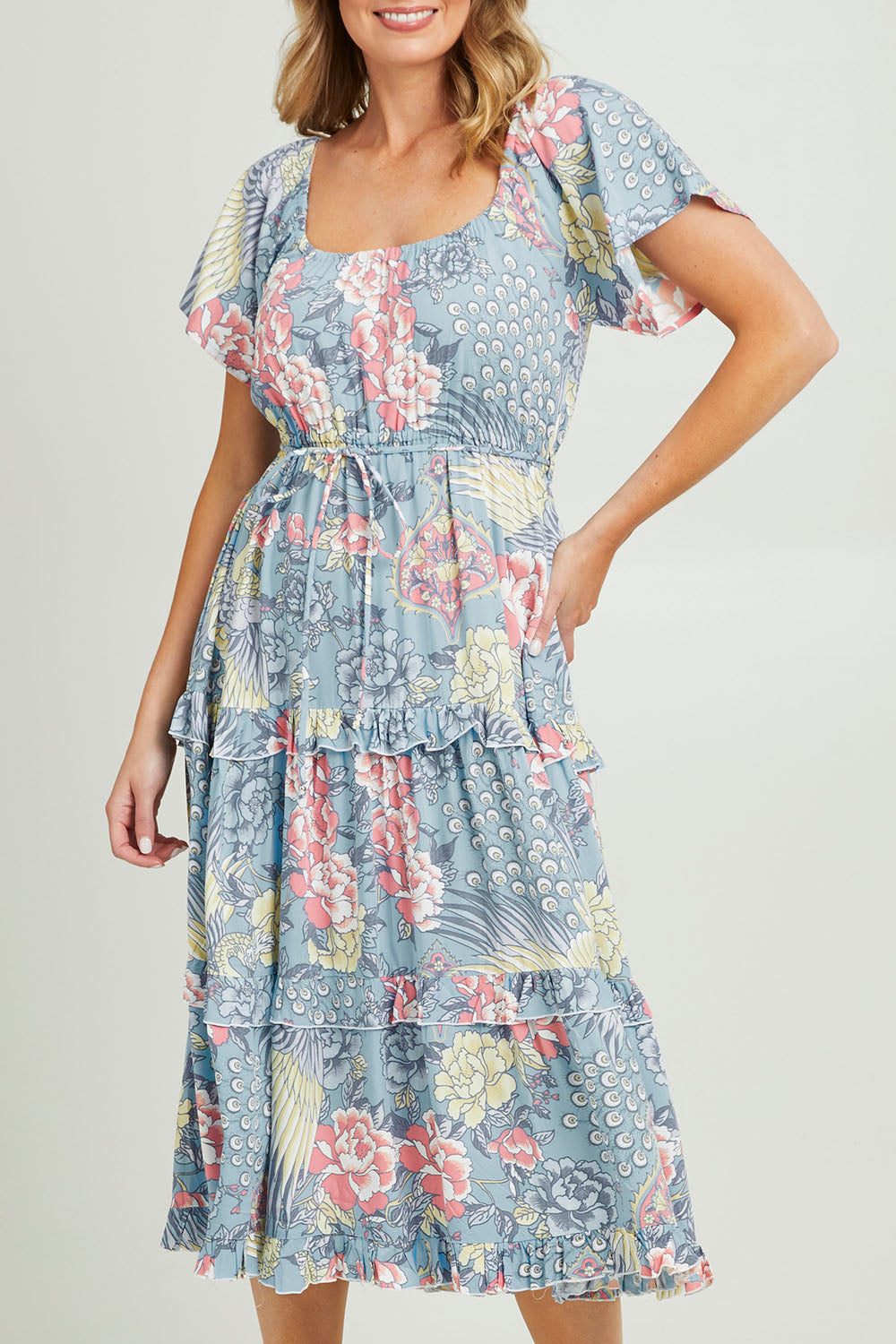 Model Grace wearing size 10 of the Siesta Dress in colour Birdgarden (Blue), from the front, cropped image