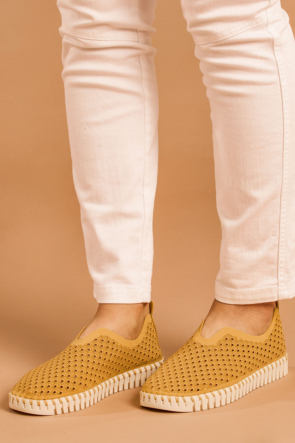 A model wearing size 38 of the Tulip Sneaker in colour Goldenrod, from the front, cropped image