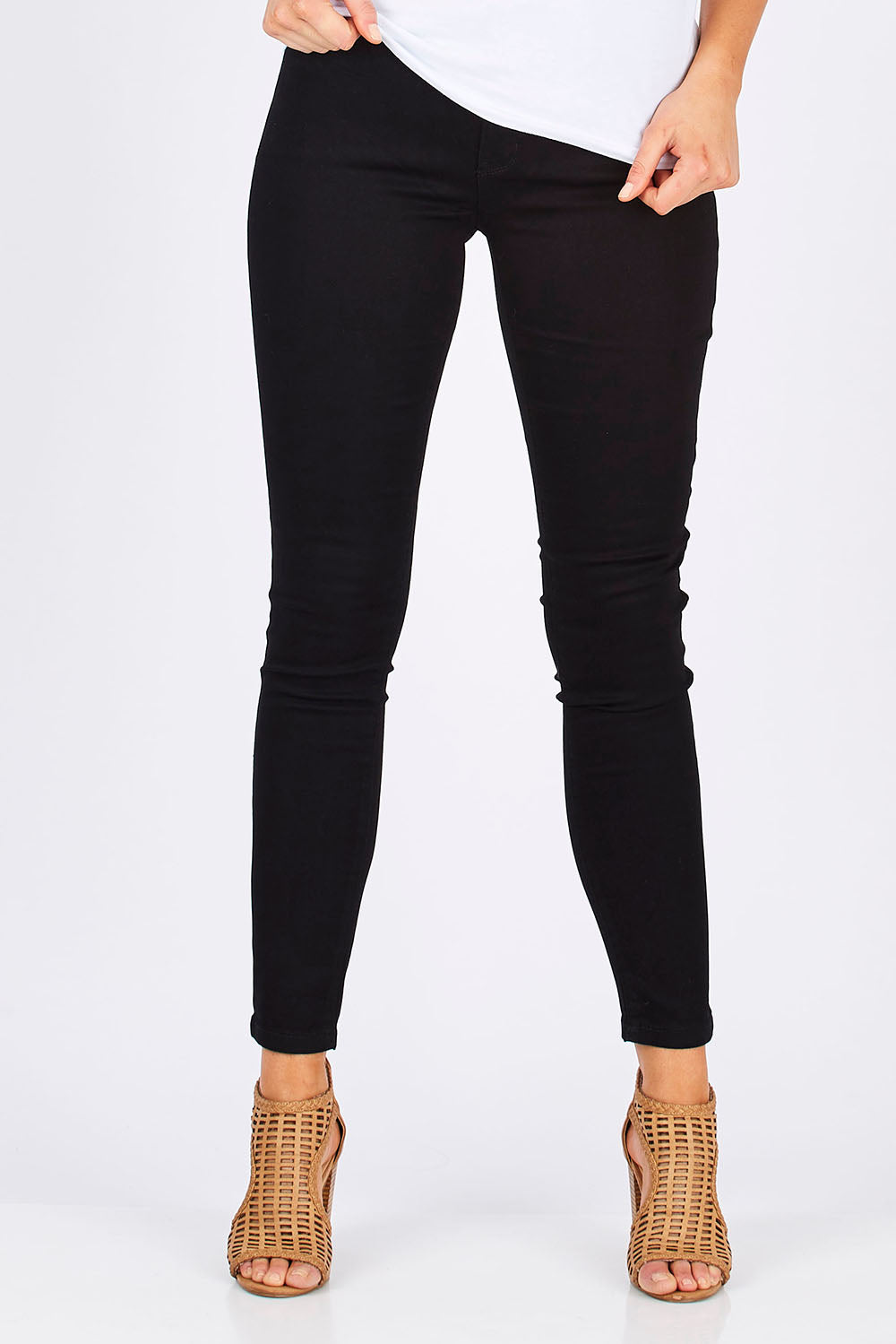Model Madeline wearing size 10 of The Twiggy Mid Rise Skinny in colour Black (Black), from the front, cropped image
