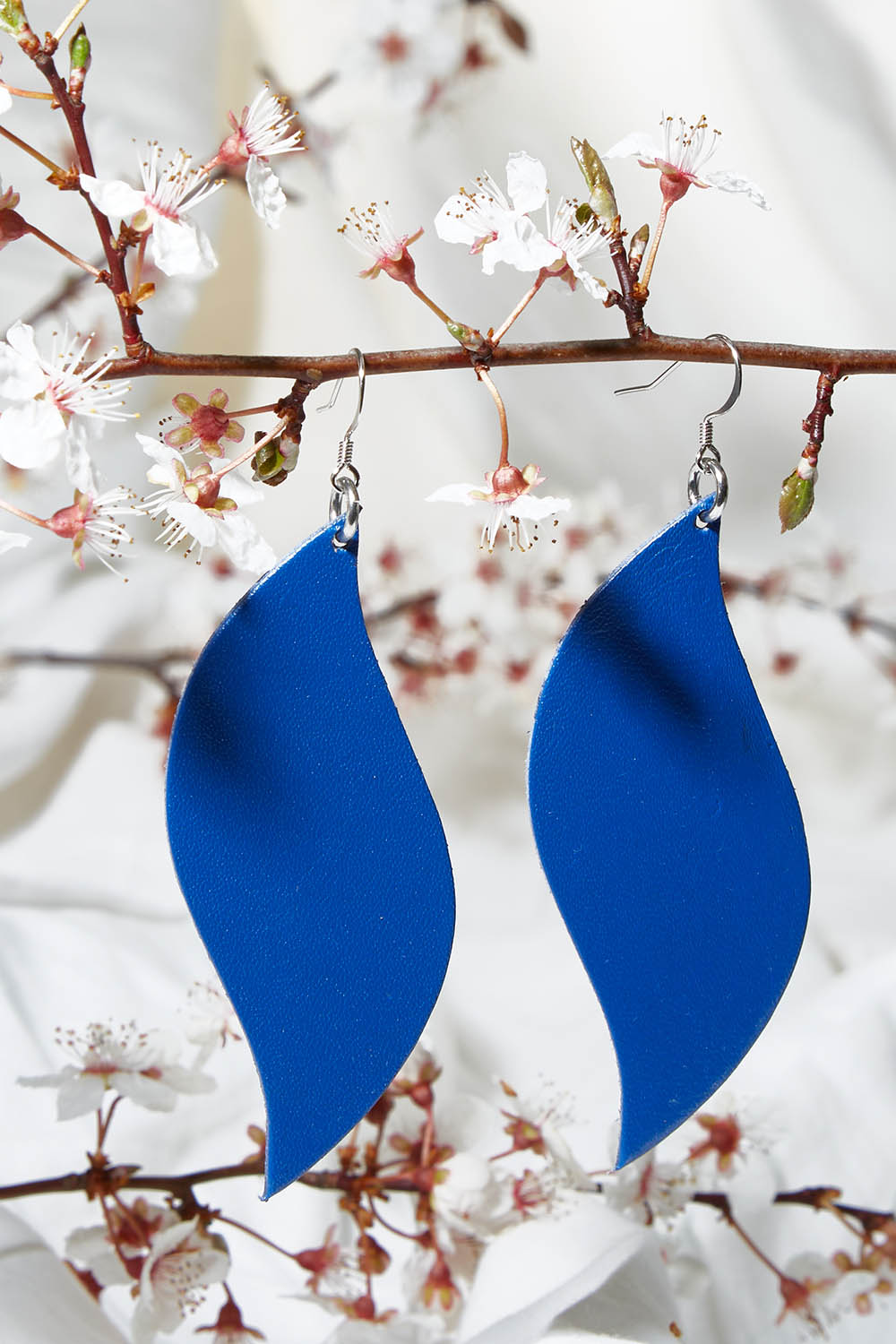 A model wearing size OneSize of the Australian Made Bold Single Leaf Leather Earring in colour Cobalt (Blue), from the front, showing the whole outfit