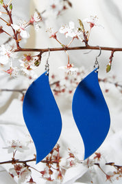 A model wearing size OneSize of the Australian Made Bold Single Leaf Leather Earring in colour Cobalt (Blue), from the front, showing the whole outfit