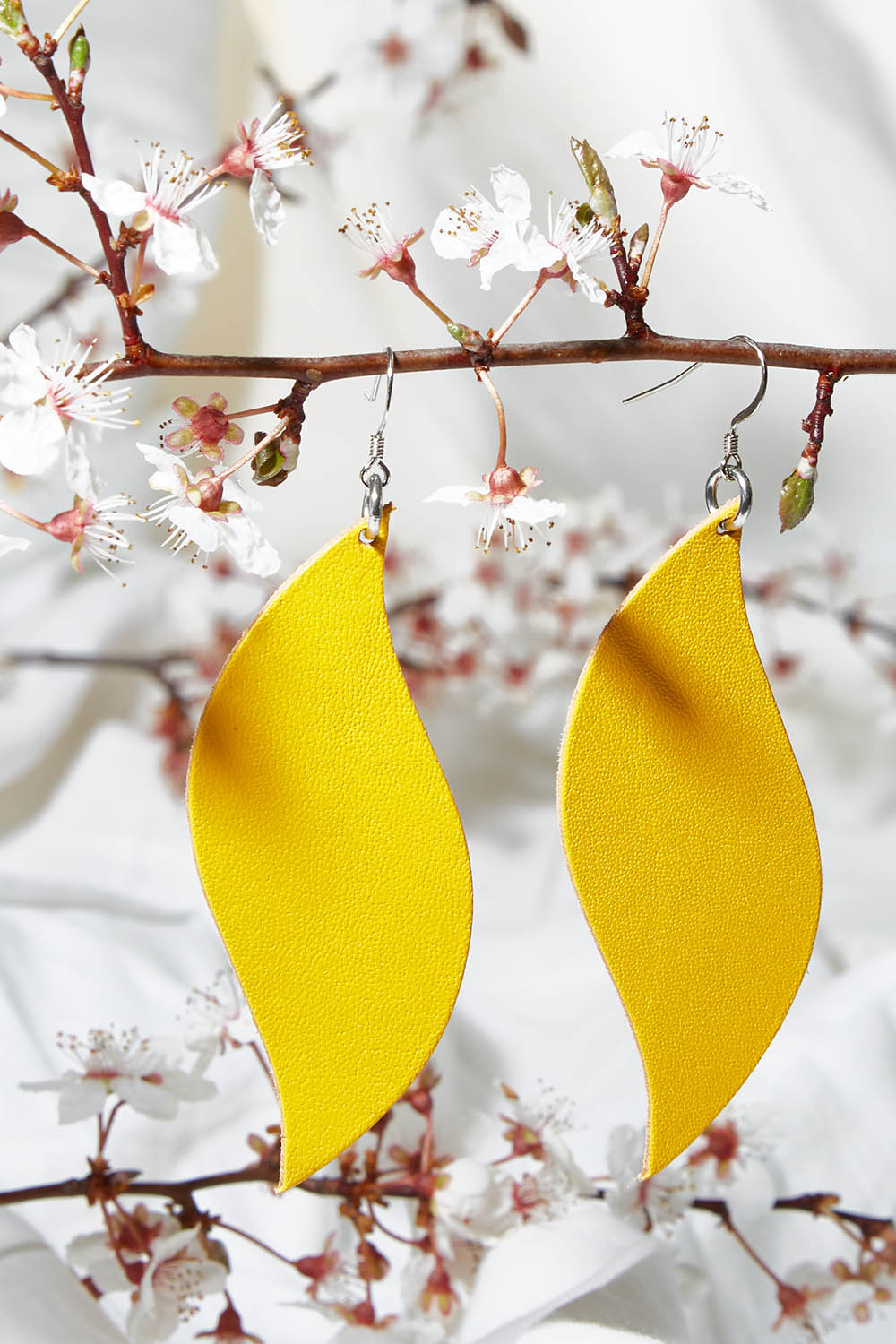 A model wearing size OneSize of the Australian Made Bold Single Leaf Leather Earring in colour Daffodil, from the front, showing the whole outfit