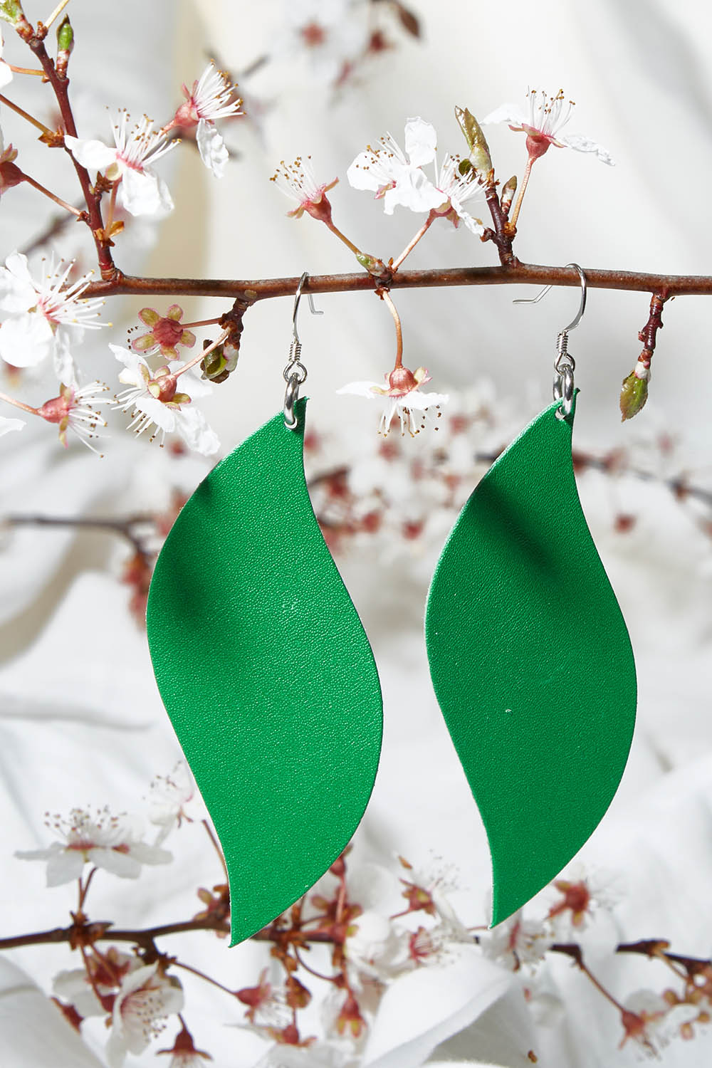 A model wearing size OneSize of the Australian Made Bold Single Leaf Leather Earring in colour Emerald (Green), from the front, showing the whole outfit