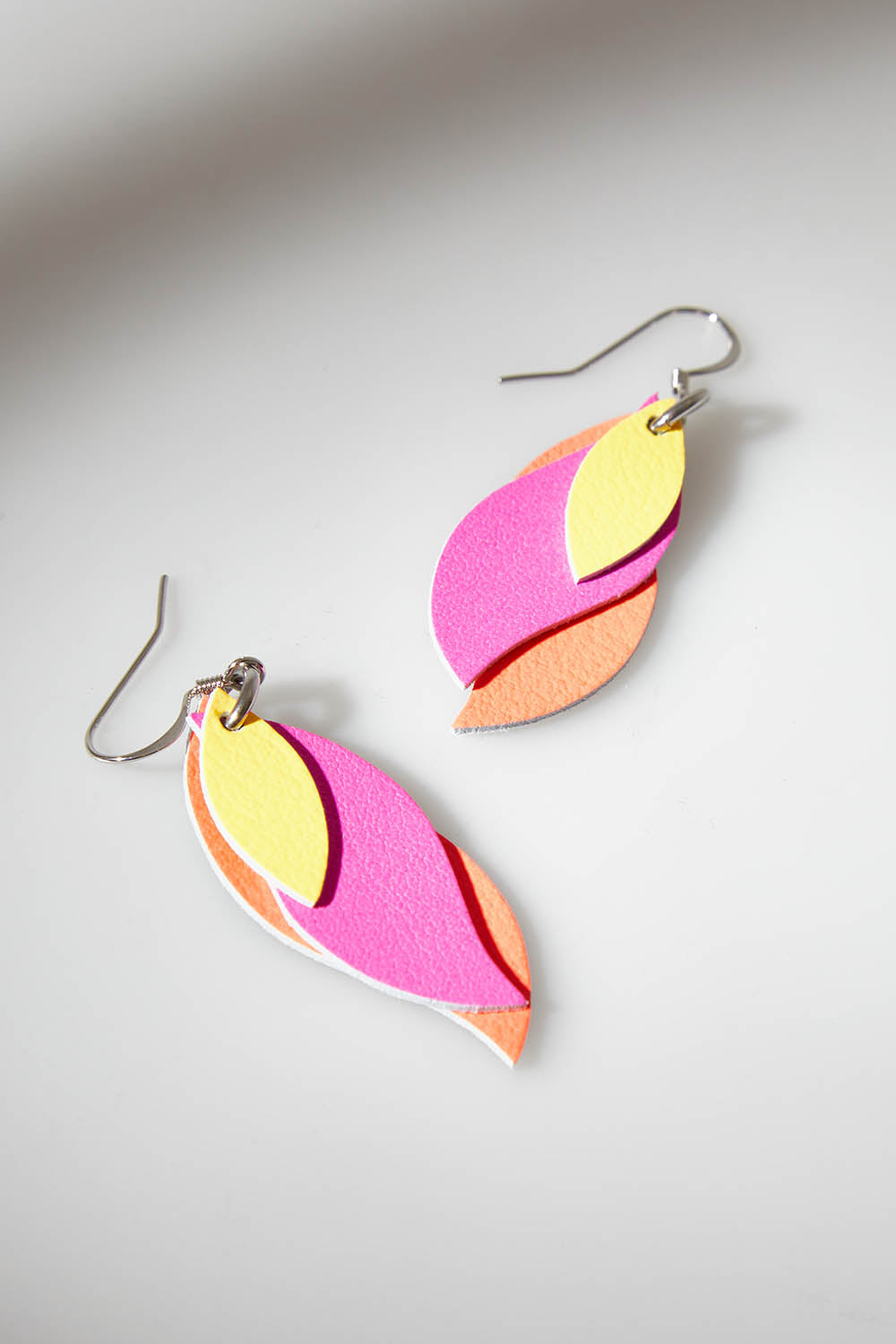 A model wearing size OneSize of the Australian Made Leather Leaf Earring in colour Orapinkyel (Pink), from the front, showing the whole outfit