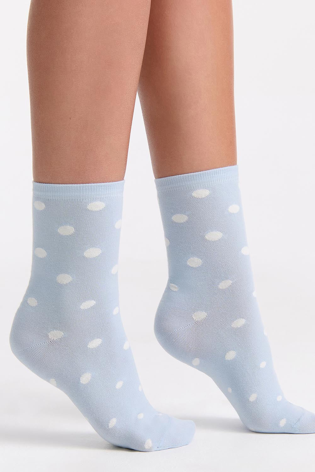 A model wearing the Gigi Spot Sock in colour Capri (Blue), from the front, cropped image