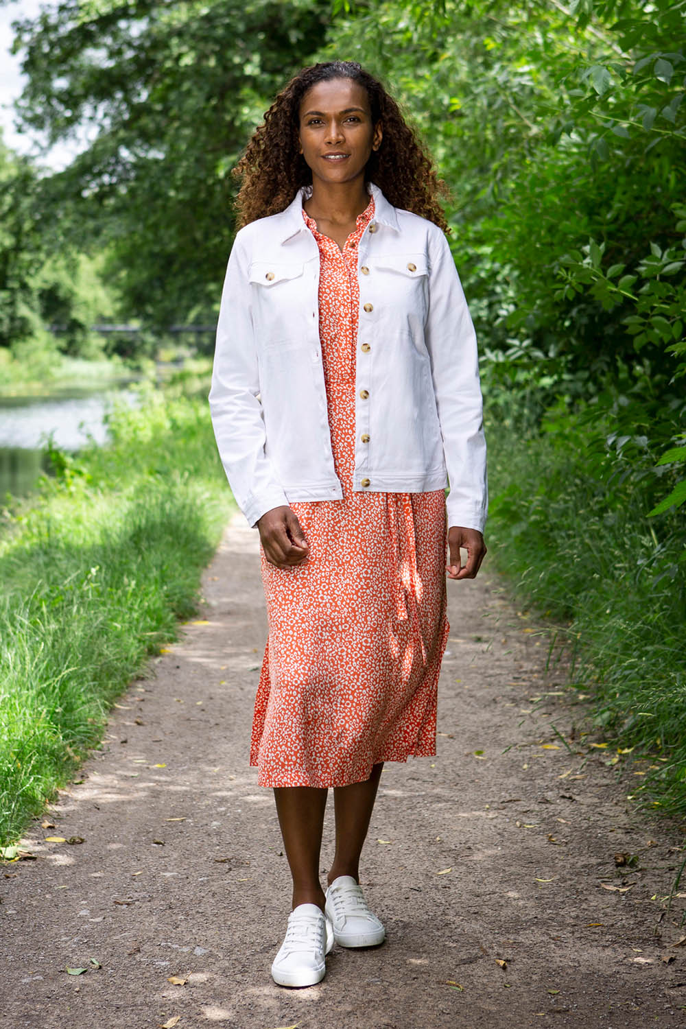 A model wearing the Causeway Dress in colour Softorang, from the front, showing the whole outfit