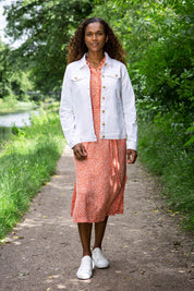 A model wearing the Causeway Dress in colour Softorang, from the front, showing the whole outfit