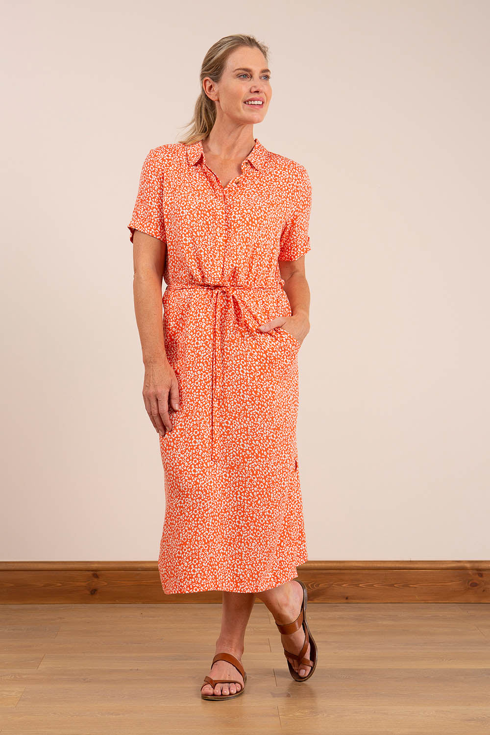 A model wearing the Causeway Dress in colour Softorang, from the front, showing the whole outfit