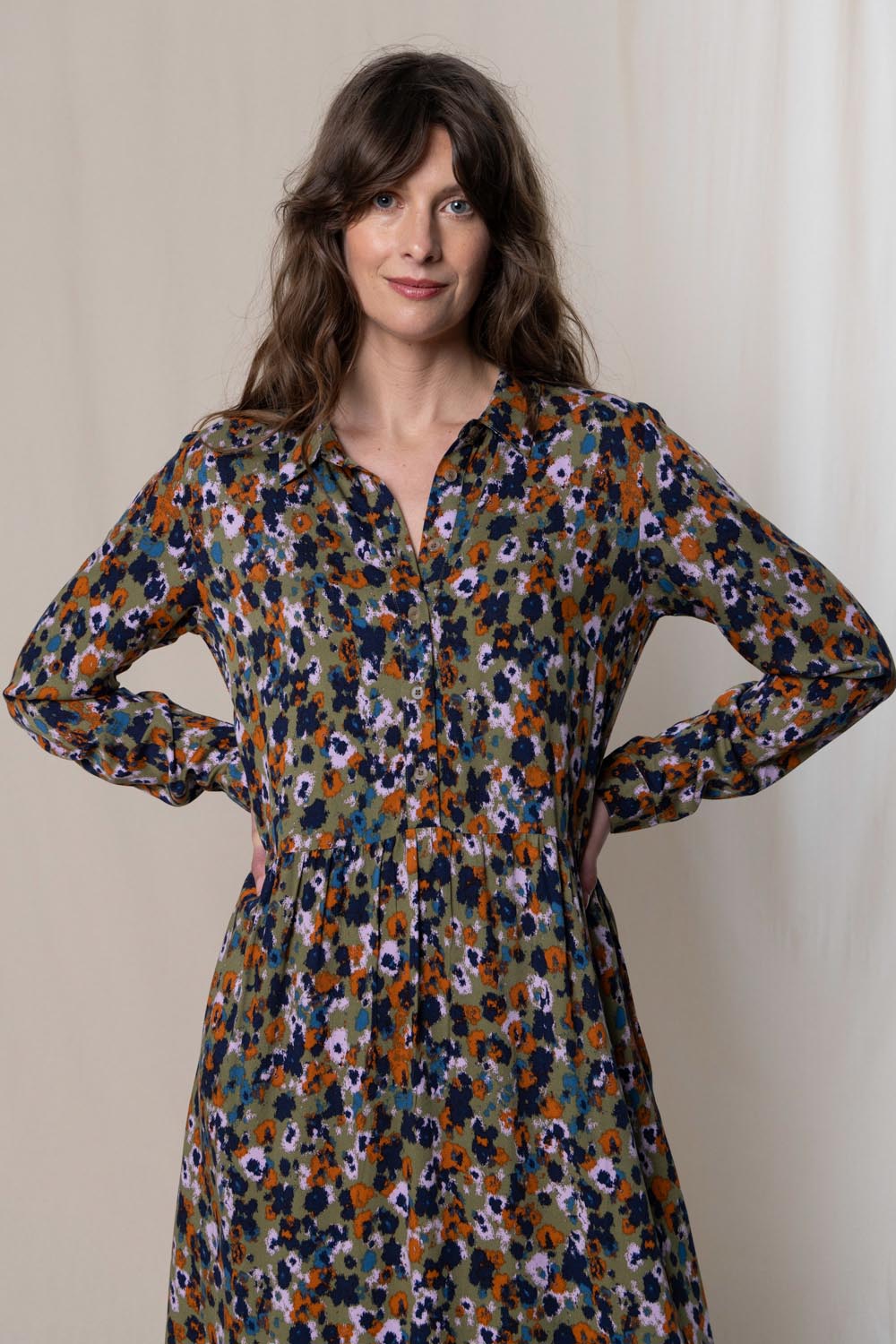 A model wearing the Seasons Dress in colour Olive (Green), from the front, cropped image