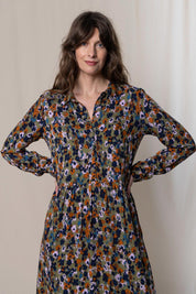 A model wearing the Seasons Dress in colour Olive (Green), from the front, cropped image
