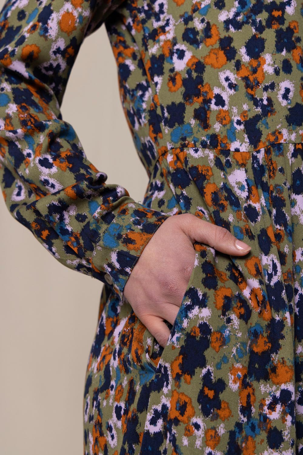 A model wearing the Seasons Dress in colour Olive (Green), from the front, cropped image