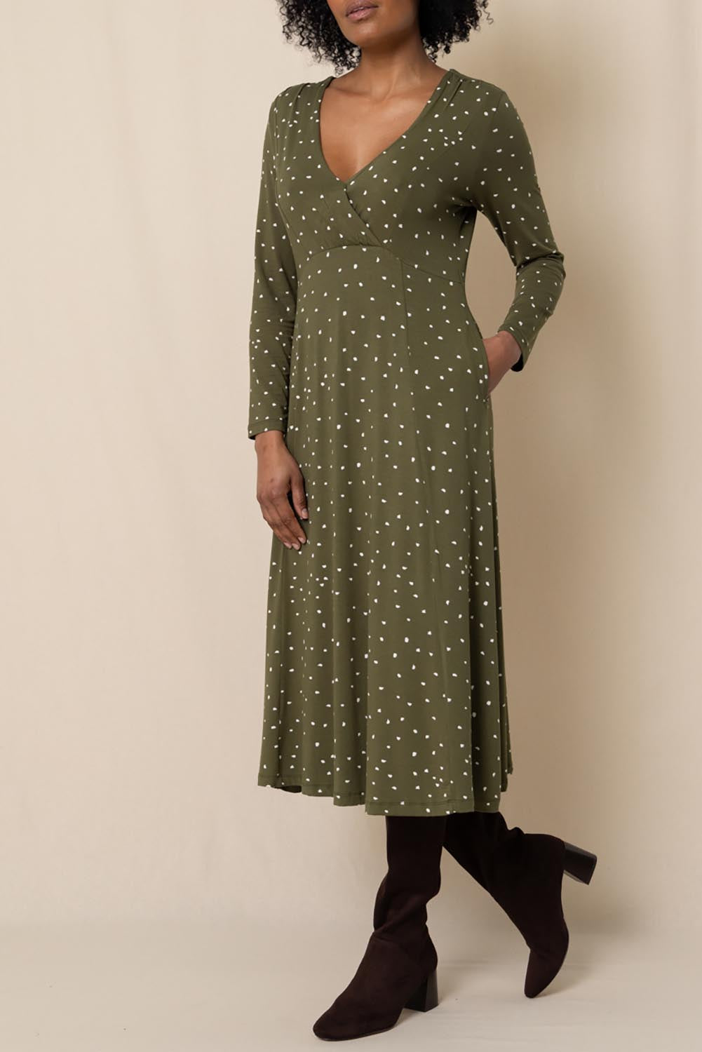 A model wearing the Rose Dress in colour Olive (Green), from the front, cropped image